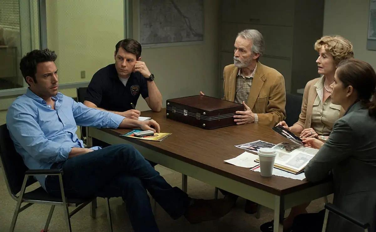 DF-11318_11319_COMP_R -- Nick (Ben Affleck, left) is questioned about the disappearance of his wife, Amy, by Detectives Boney (Kim Dickens, far right) and Gilpin (Patrick Fugit, in dark shirt), as Nick’s in-laws Marybeth and Rand Elliott (Lisa Barnes, David Clennon) look on.