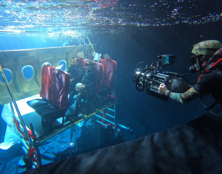 A person filming actors underwater