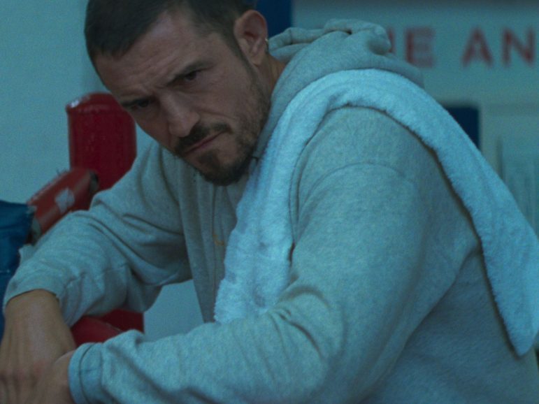 Orlando Bloom sat in a grey sweatsuit with towel on his shoulder