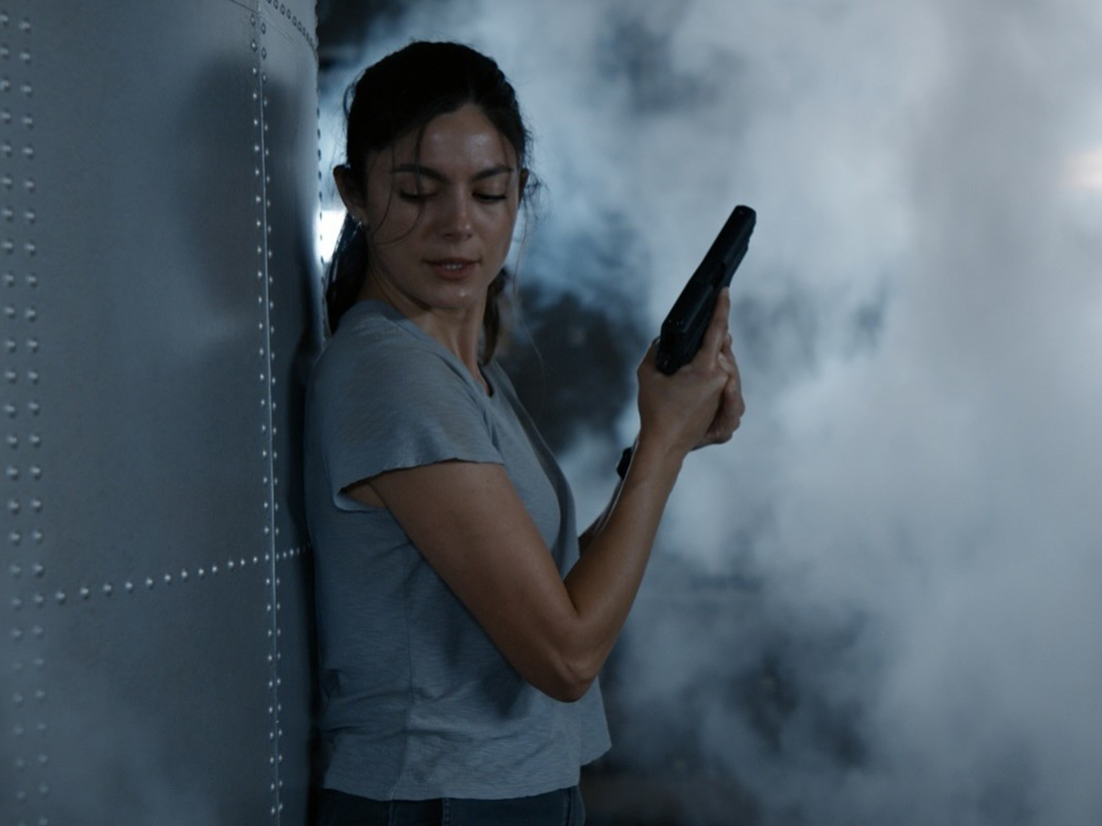 A woman standing holding a pistol