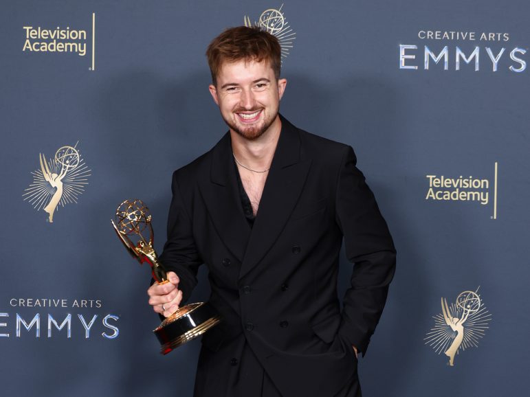 A man smiles while holding an award
