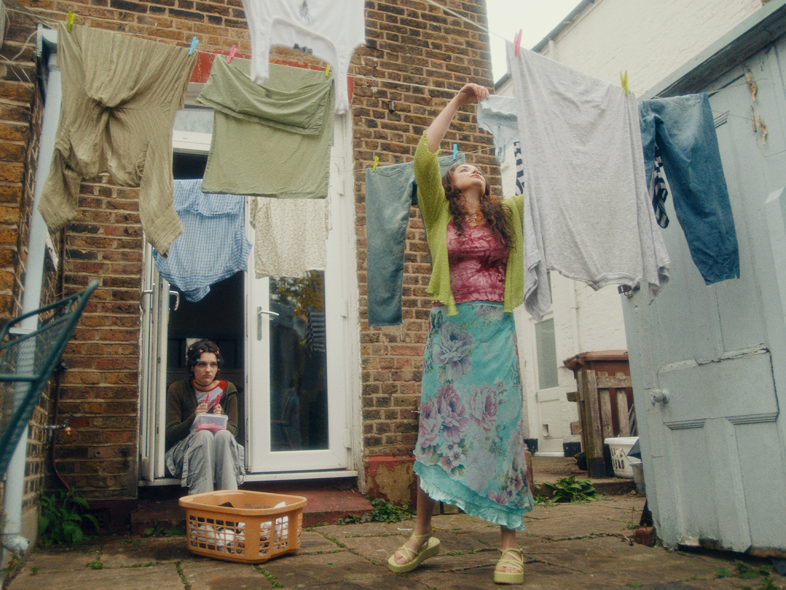 A person watching another person hanging up washing