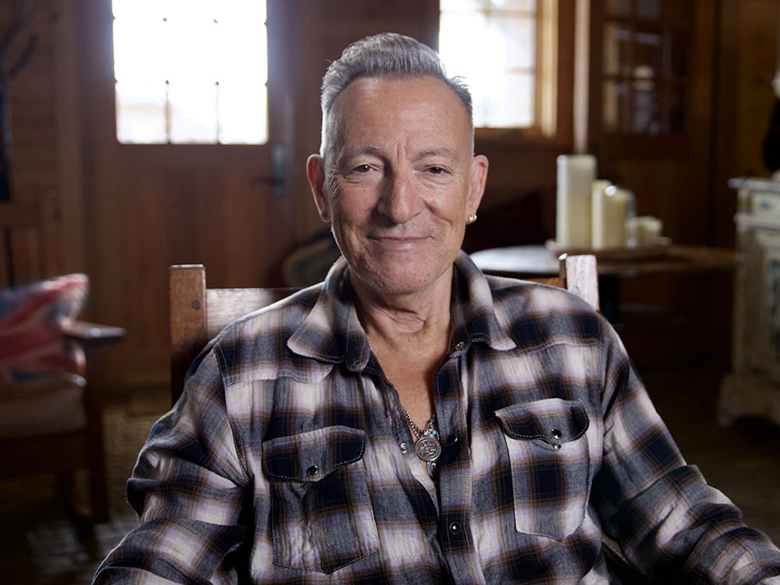 Bruce Springsteen sat in a chequered shirt looking into camera