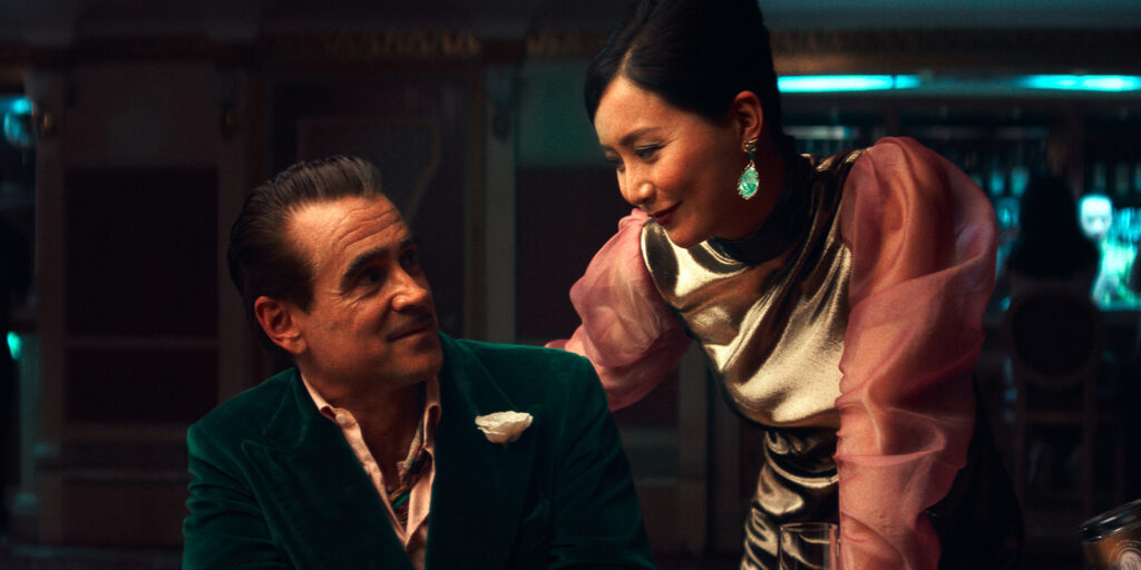 A man looks up at a woman, smiling, in formal attire