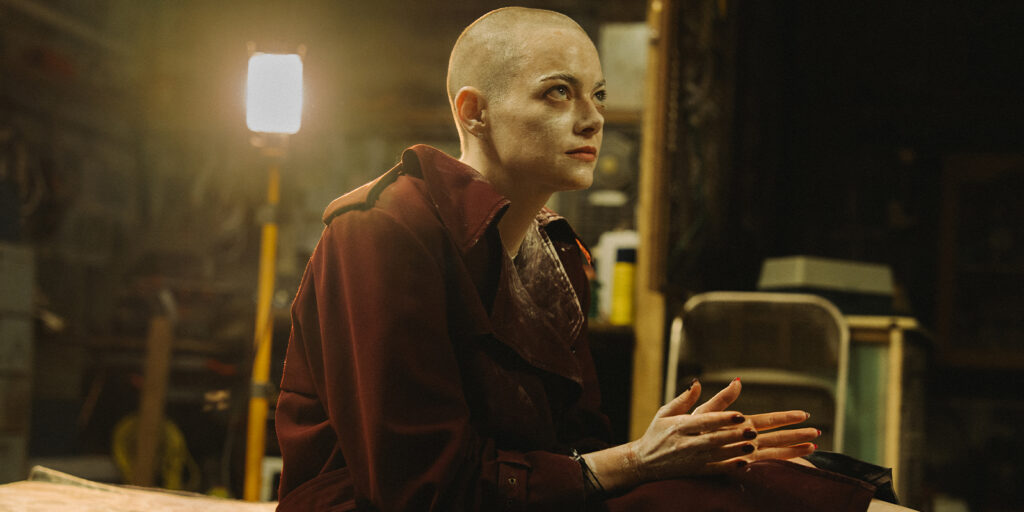 Emma Stone with a shaved head in a basement