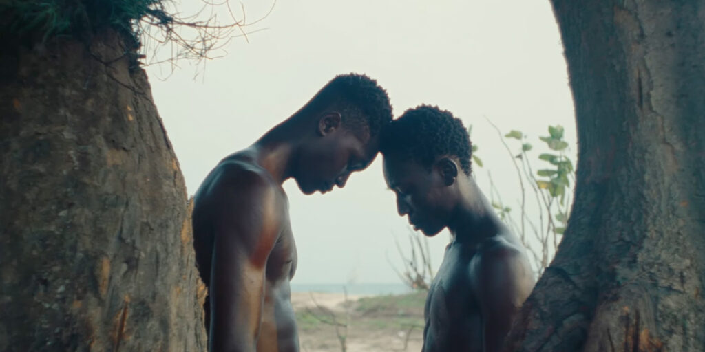 Two people leaning their heads on one another on a beach