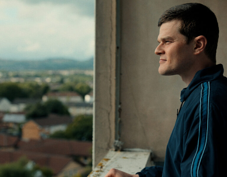 A man on a balcony smiling