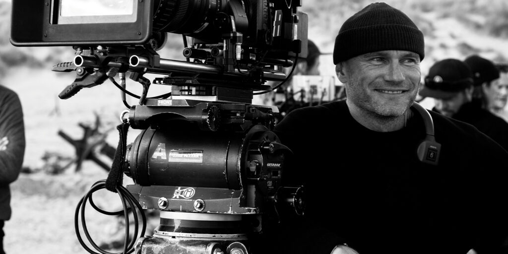 A man smiling by a camera