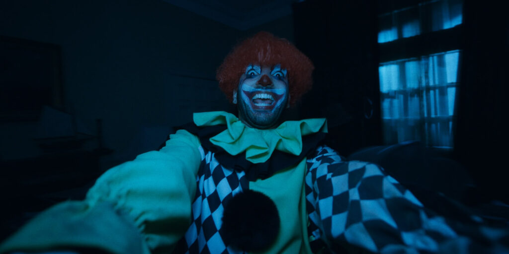 A man in a clown outfit staring into camera