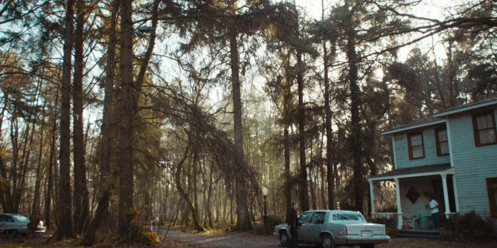 A lodge in the woods with a car outside 