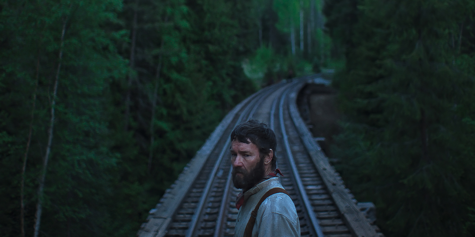 Joel Edgerton standing in front of a train line