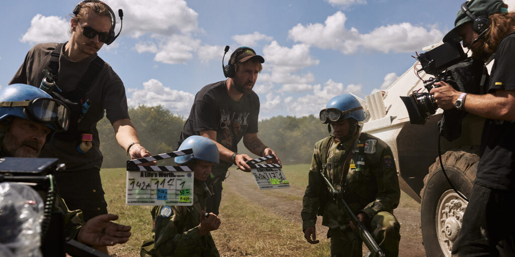 Film crew filming soldiers in a field