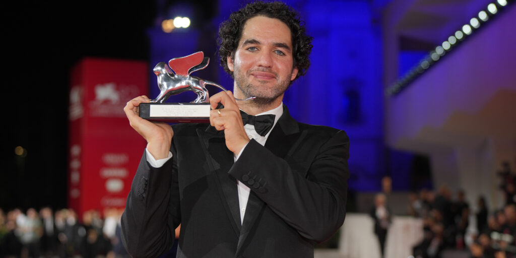 Benny Safdie holding a trophy on the red carpet