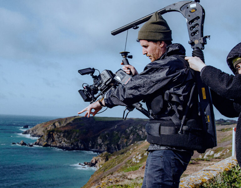 A camera operator and crew member by the sea