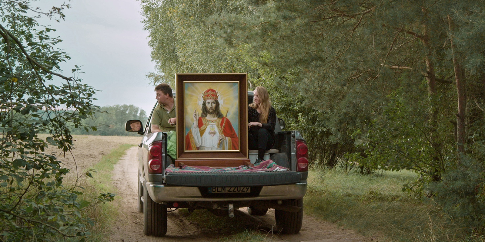 Two people on a truck with a painting of Jesus