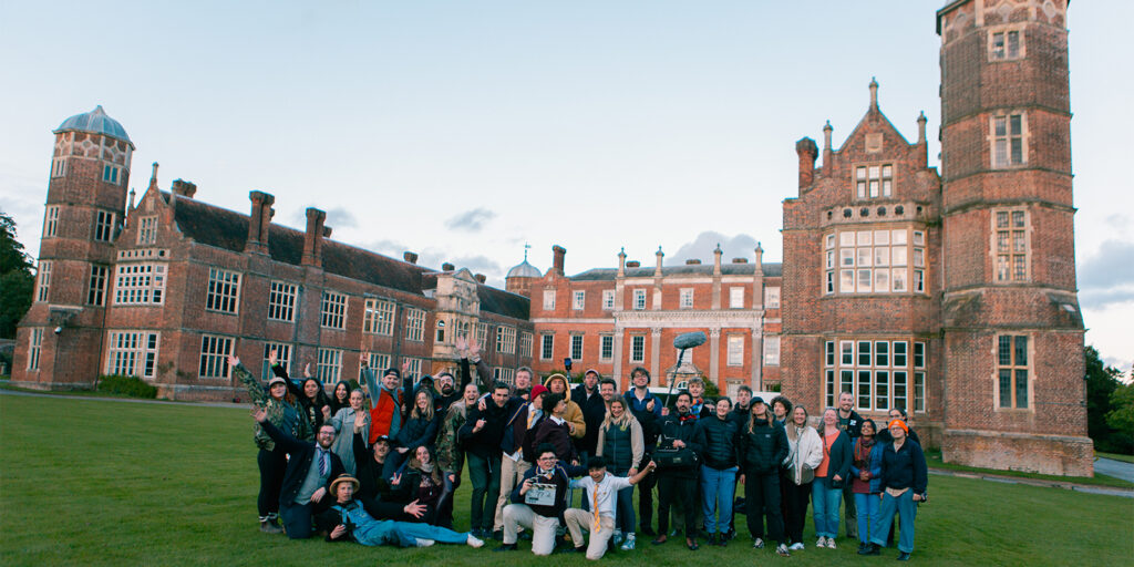 Film crew posing together outside a large building