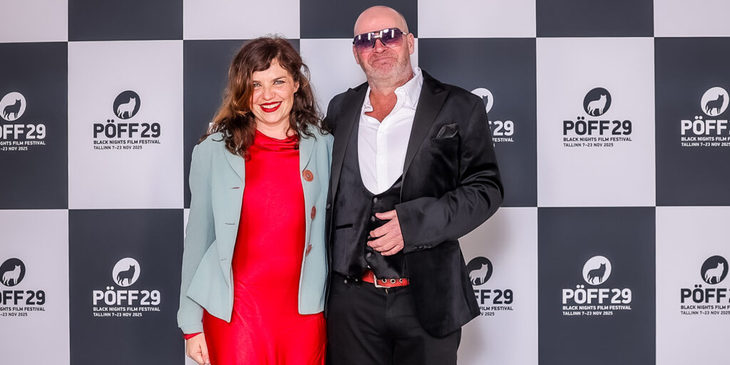 Two people smiling on a red carpet