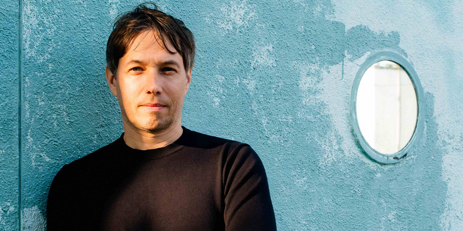 Sean Baker leaning on a blue wall