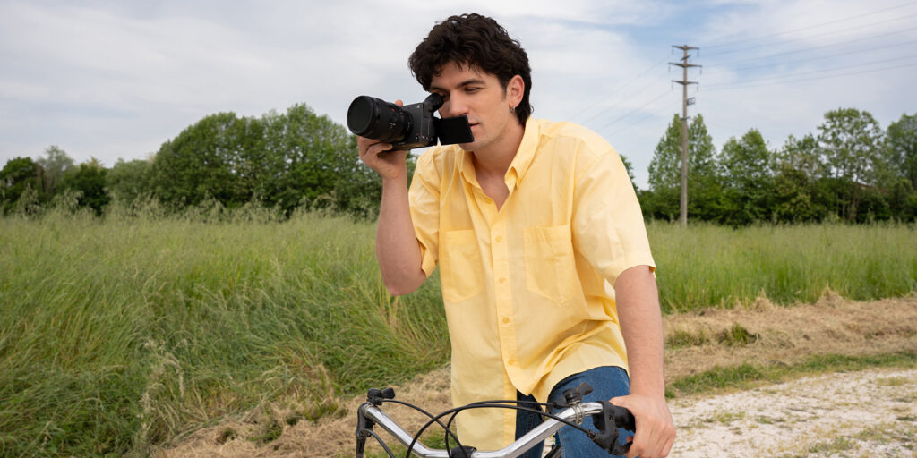 A man on a bike looking through a camera