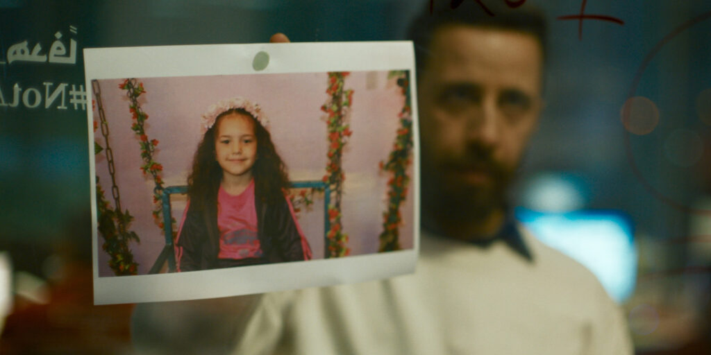 A man holding up a picture of a girl
