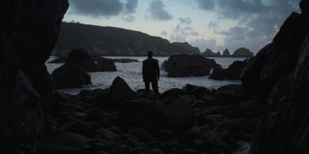A man stood by the sea at night