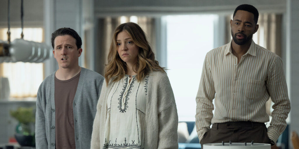 Three people stood in a kitchen looking concerned 