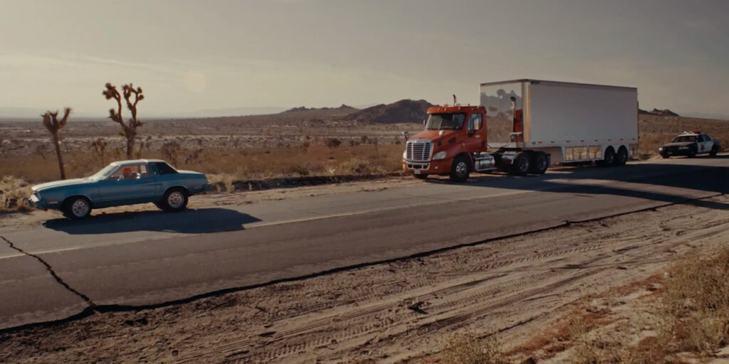 A car followed by a truck followed by a police car