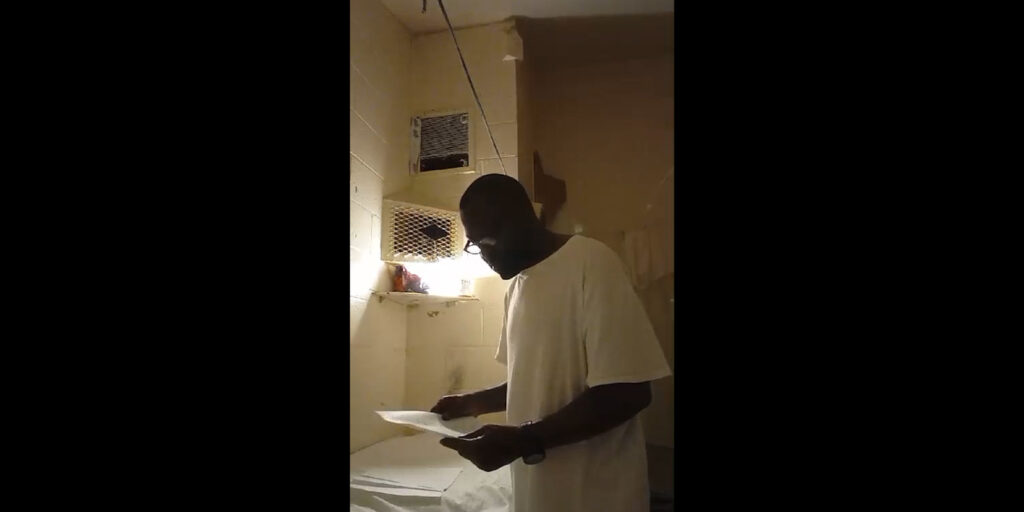A man in a cell looking at paper