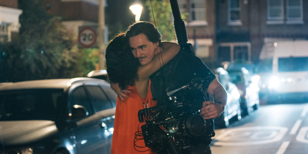 Charlie Knight holding a camera while hugging a woman