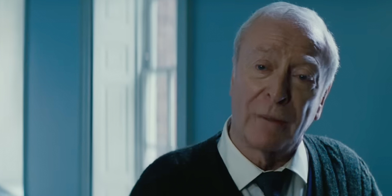 Michael Caine stood in a shirt and cardigan