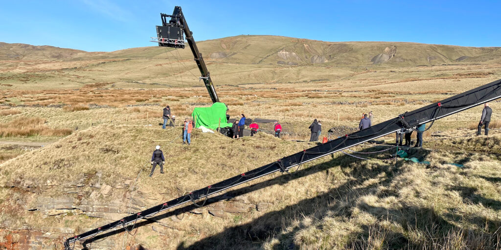 A camera crane and crew in a field 