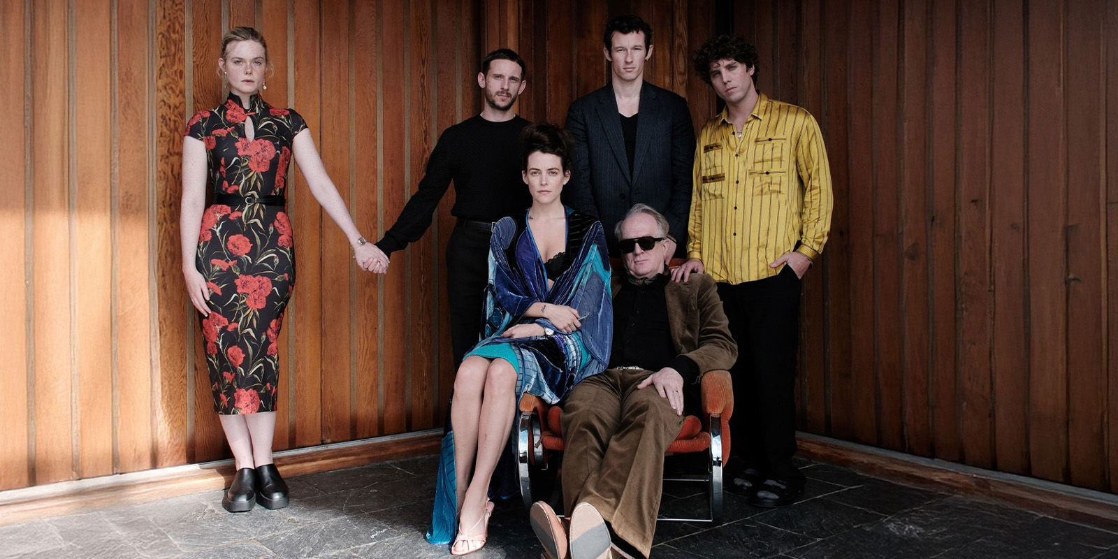 A group of people posing by a wooden wall
