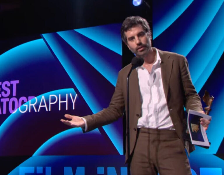 Adolpho Veloso on stage holding an award