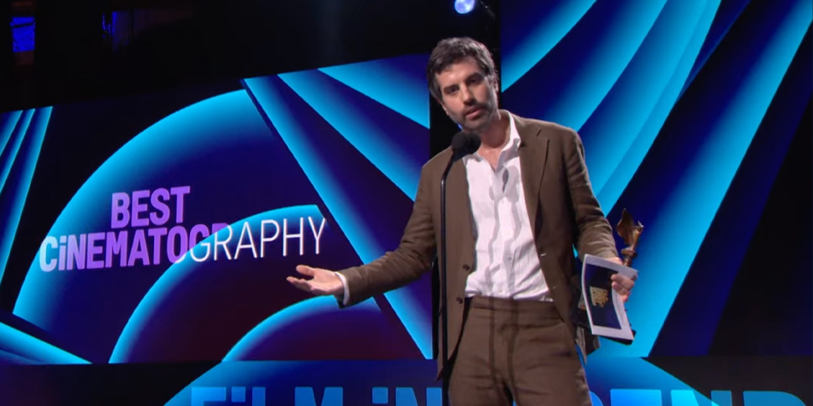 Adolpho Veloso on stage holding an award