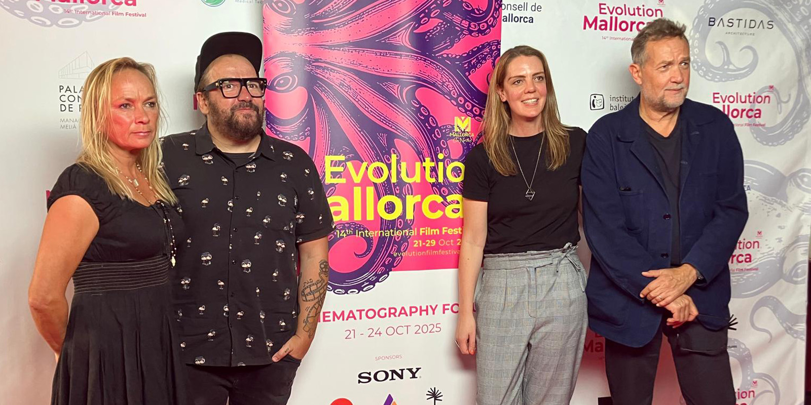 Four people stand side by side posing for a photo at the Evolution Mallorca International Film Festival. They are in front of a step-and-repeat banner featuring festival logos and sponsors from the Film Festival 2026.