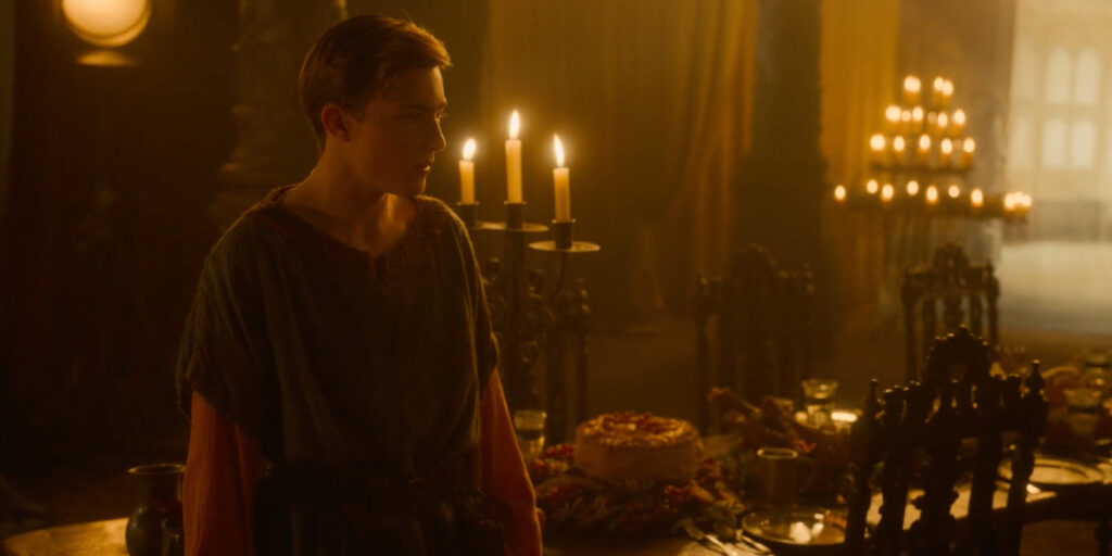 A young person stands beside a banquet table with lit candles, food, and a cake in a dimly lit room with dark furniture and warm yellow lighting, reminiscent of an adventure from The Famous Five.