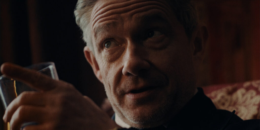 Martin Freeman holding a glass and talking