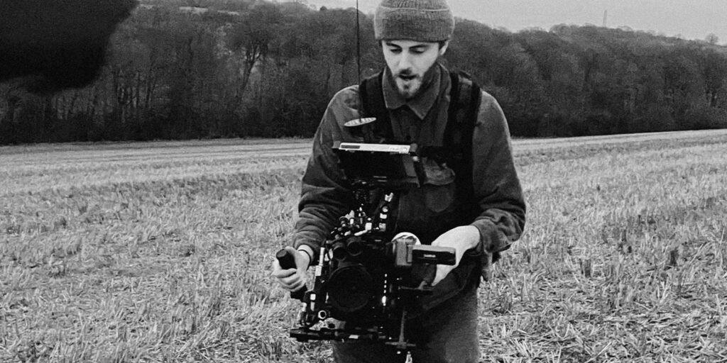 A man operating a camera in a field 