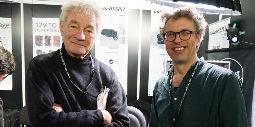 Two men stand side by side at the BSC Expo 2026, both wearing dark jumpers and lanyards. They are smiling at the camera, with exhibition posters and lighting equipment visible in the background for this Event Review.