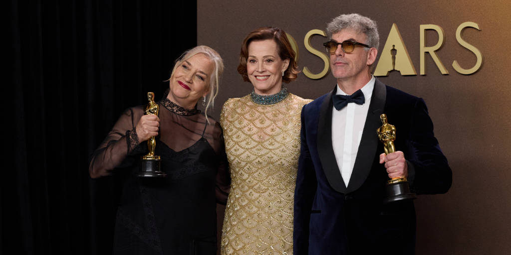 Tamara Deverell, Sigourney Weaver, and Shane Vieau pose backstage with the Oscar for Production Design