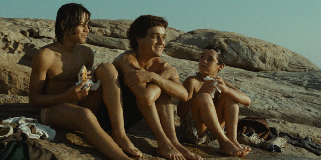 Three boys sat by the sea