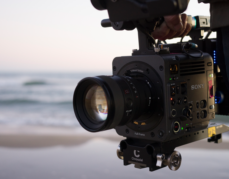 A person holding a camera on a beach