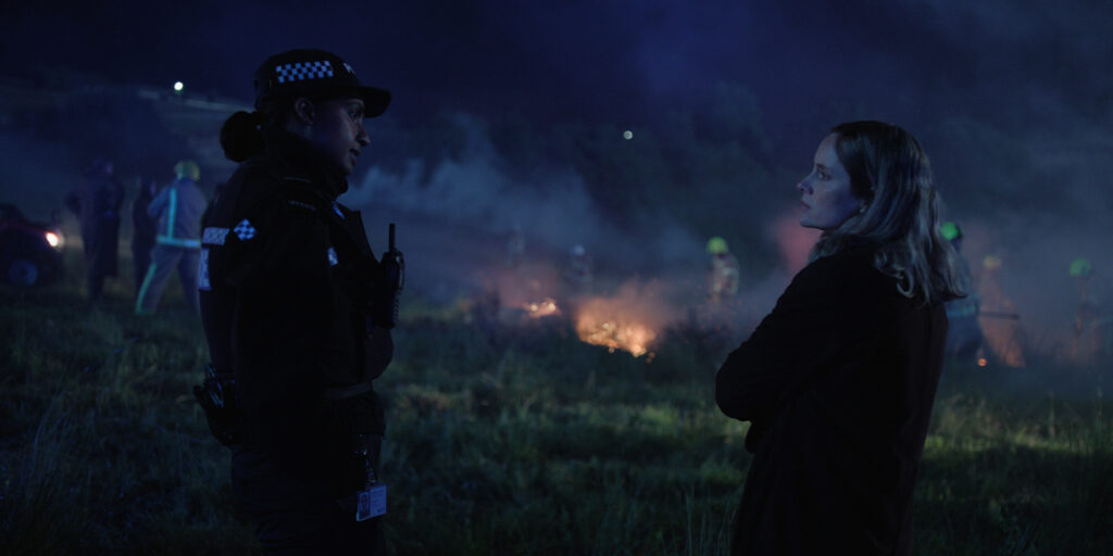 Two people standing by a fiery night sky