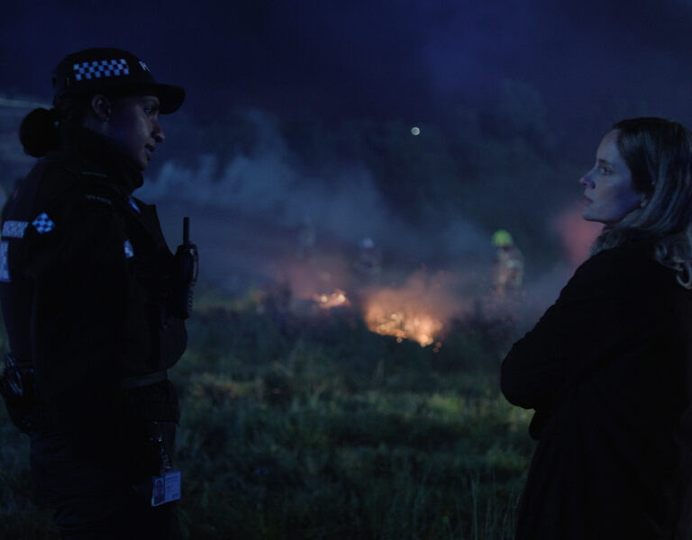 Two people standing by a fiery night sky