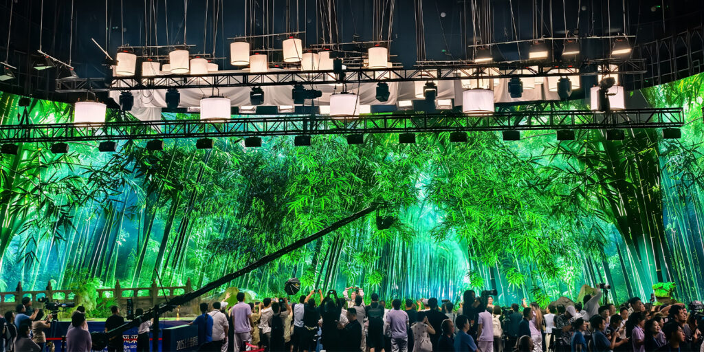 A large green virtual production screen with people below