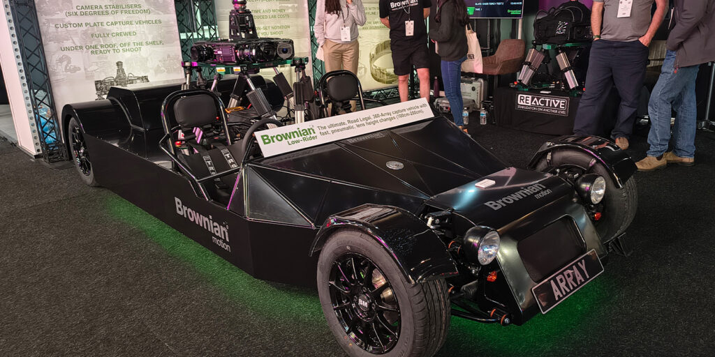 A custom-built, open-frame black car rig with mounted camera equipment is displayed indoors at a BSC Expo 2026 stand. Informational posters and people with lanyards set the scene for this event review.