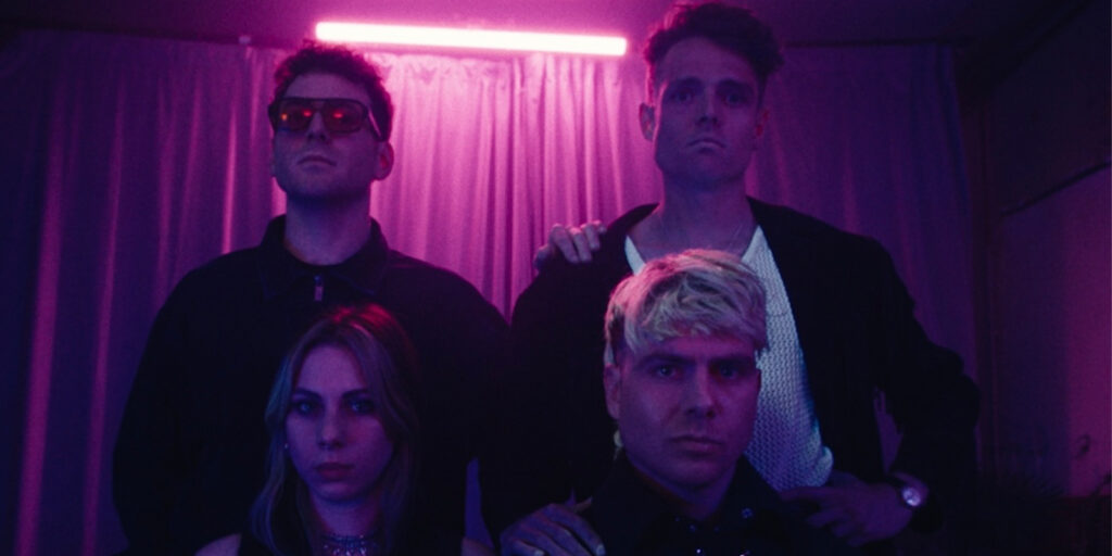 Four people stood together under neon lights