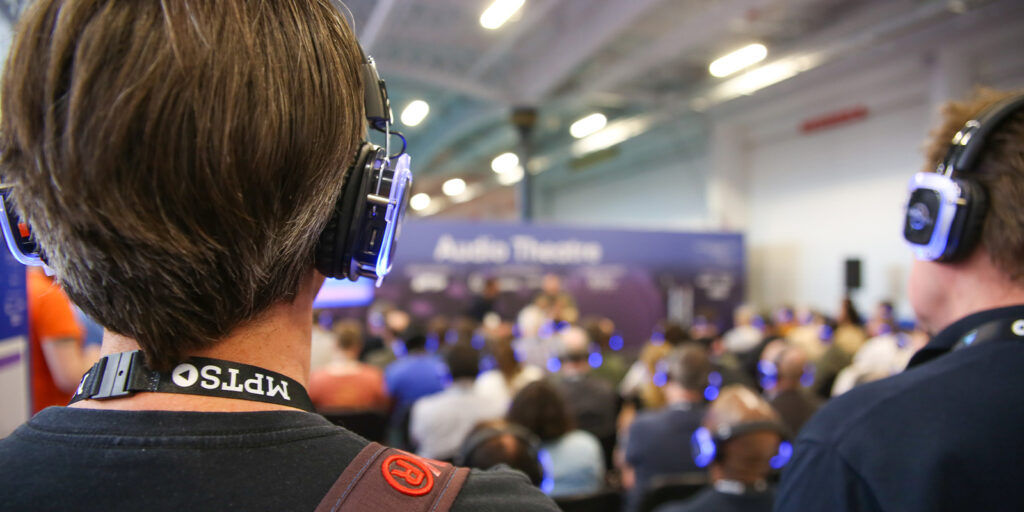 A crowd of people sat wearing headphones