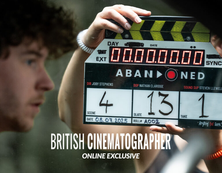 A man sat with a clapperboard in the background