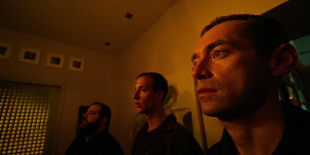 Three people stood in a room looking tense